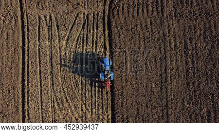 Tractor Driver On Tractor Plows Land. Aerial. Farmer In Tractor Plowing Ground