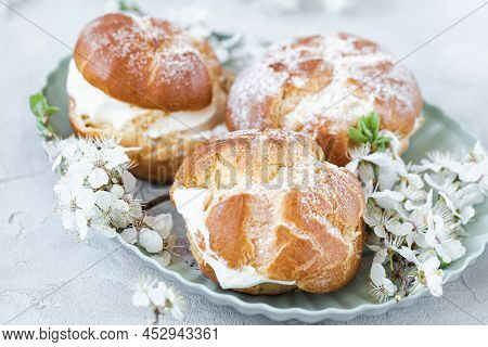 Choux Buns With Whipped Cream And Sugar Powder On Top On Plate. Gray Background With Spring White Ch