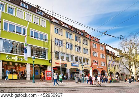 Freiburg, Germany - April 2022: City Center With Shops And People Walking By On Sunny Spring Day