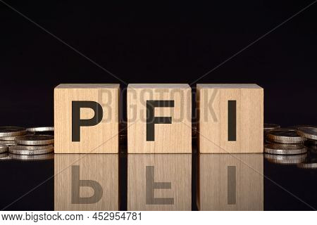 Pfi - Short For Private Finance Initiative. Text On Wood Cubes With Coins, Black Background, Busines