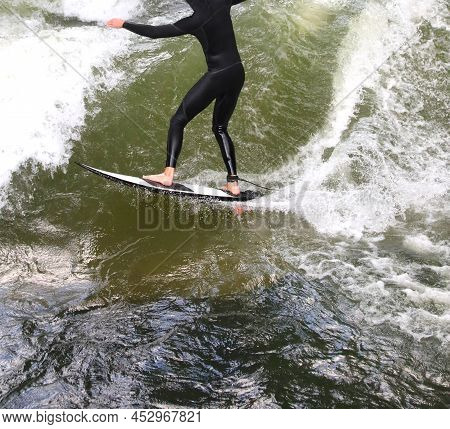 Young Surfer Athlete With Wetsuit Rides The Waves While Staying In Balance