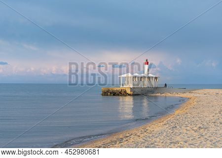 Lighthouse And Gazebos In The Sea During Dawn. Calm On The Sea. Seaboard, Seascape.