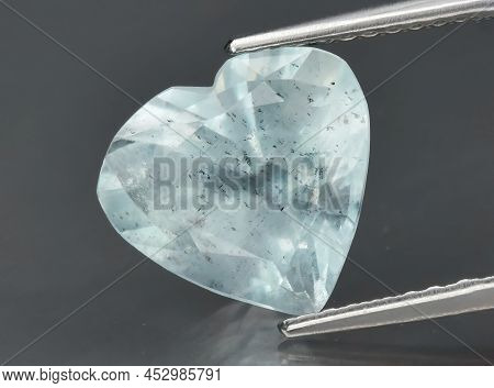 Natural Gemstone Blue Aquamarine In Tongs On A Gray Background