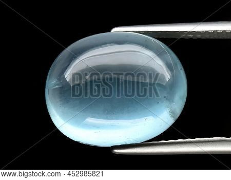 Natural Gemstone Blue Aquamarine In Tongs On A Gray Background
