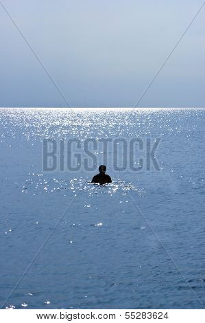 Silhouette of a Man Swimming on a Beach