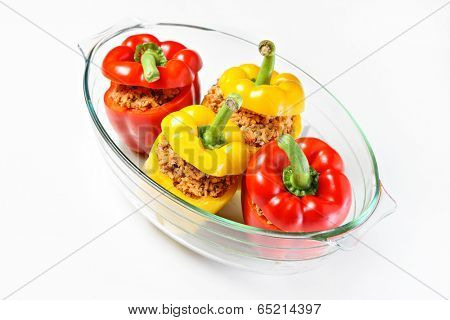 A picture of an unbaked yellow and red stuffed peppers served in a heatproof glass