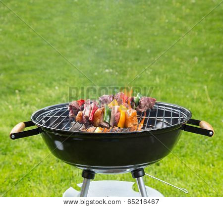Meat and vegetable skewer on barbecue grill with fire