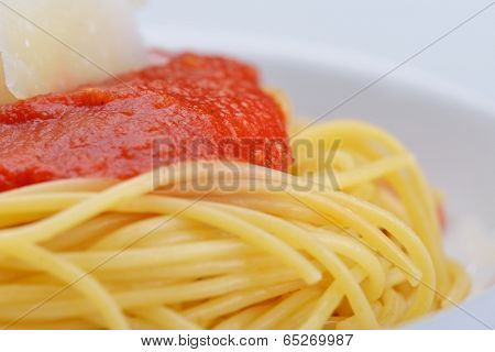 Italian spaghetti topped with bolognaise, or bolognese, sauce with tomatoes, meat and cheese on a plain white plate