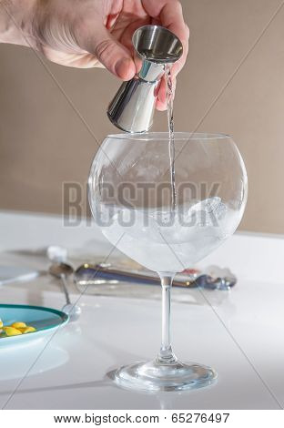 Barman pouring drink to prepare gin tonic cocktail