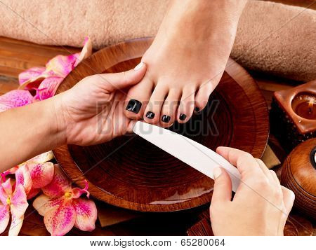 Pedicurist master makes pedicure on woman's legs - Spa treatment concept