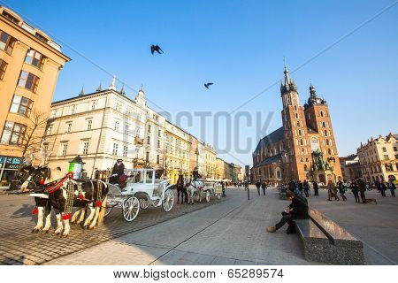 KRAKOW, POLAND - FEB 26, 2014: Carriages at Main Market Square. It dates to the 13th century, and at roughly 40,000 m it is the largest medieval town square in Europe.