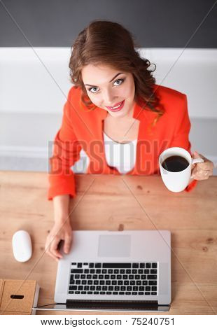 Attractive woman sitting at desk in office, working with laptop