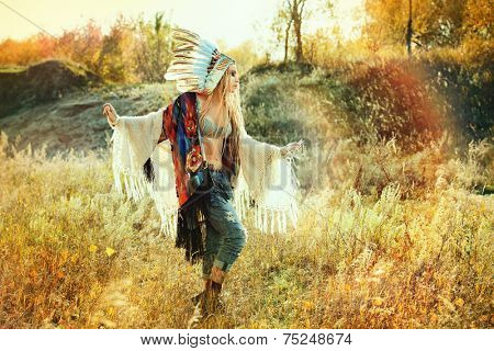 Beautiful girl in style of the American Indians dancing in the rays of the autumn sun. Western style. Jeans fashion.