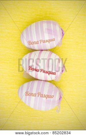 bona pascua against three purple easter eggs