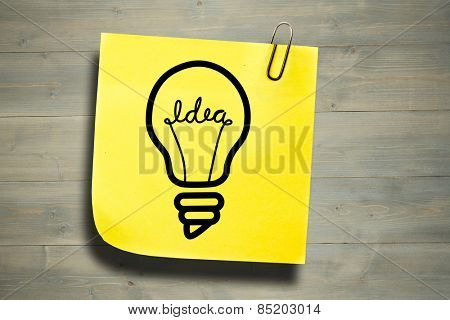 Light bulb against sticky note with grey paperclip