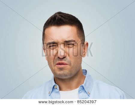 emotions, facial expression and people concept - man wrying of unpleasant smell over gray background