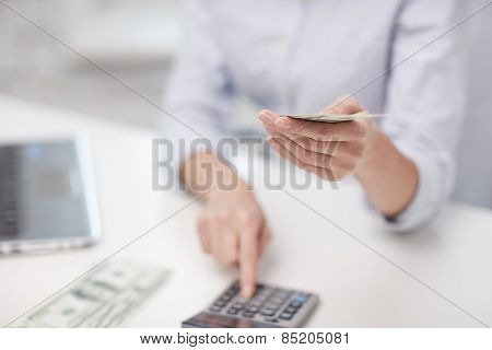 savings, finances, economy, technology and people concept - close up of woman counting money with calculator