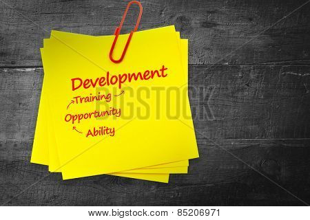 Development list against sticky note with red paperclip