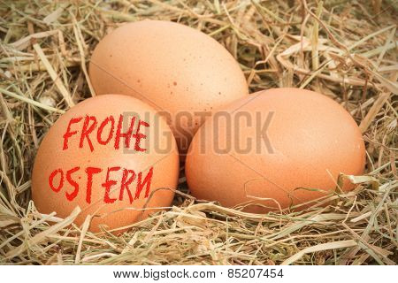 frohe ostern against three eggs nestled in straw