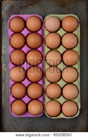 High angle shot of two one dozen cartons of organic brown eggs on a well used cooking surface.. Vertical format.