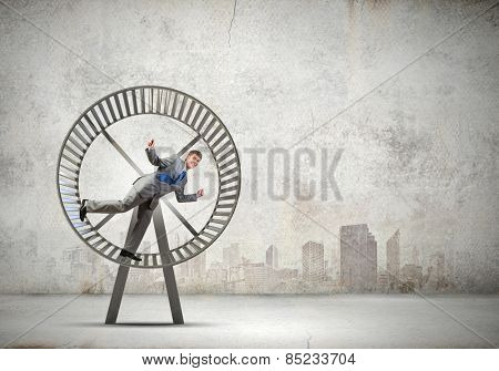 Young businessman running in huge hamster wheel
