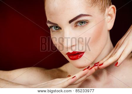 Beautiful young model with red lips and red manicure on black background