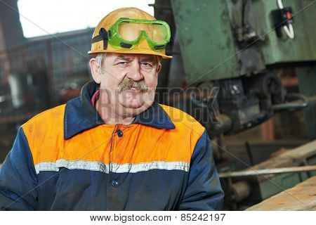 adult industrial worker at spot welding machine in factory workshop