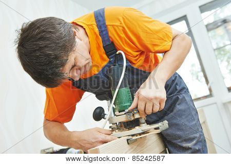 door installer working with milling cutter at preparing hole for hinge