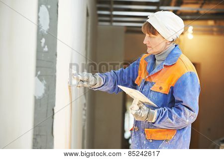 Plasterer at indoor wall renovation stucco decoration with float and plaster