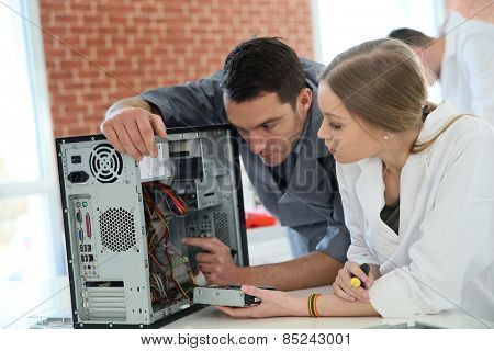 Teacher with student in technology repairing computer