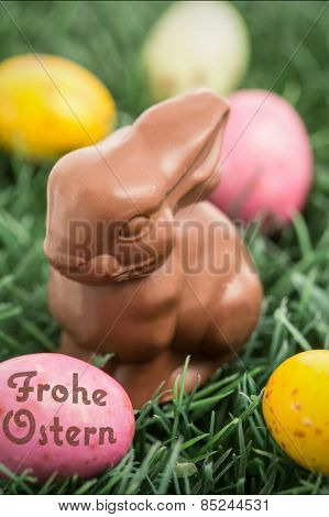 frohe ostern against colourful easter eggs with chocolate bunny