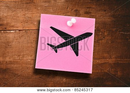 Airplane against pink adhesive note with pushpin