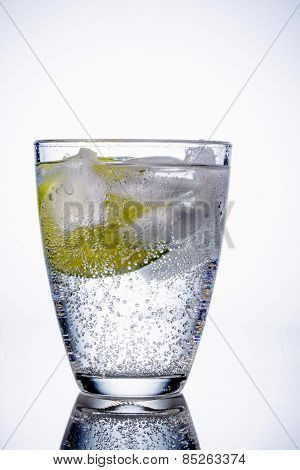 a glass of fresh drinking water and a lime. bottled water as a thirst quencher.