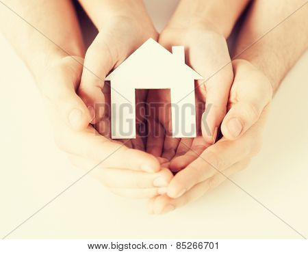 pisture of man and woman hands holding paper house