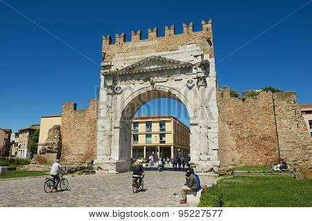 People pass under Augustus Arch - the ancient romanesque gate and the historical landmark of Rimini.