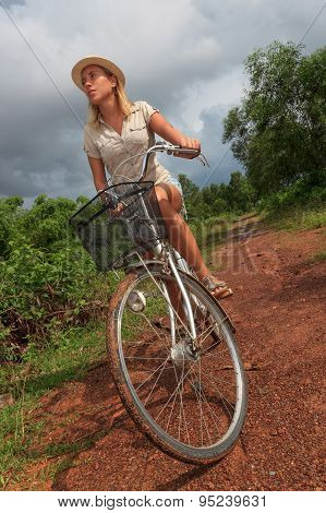 Young Blond Woman Riding A Bicycle In Countryside