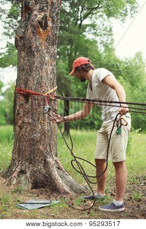 Man Prepares The Equipment Fixes Secures The Rope To The Tree For Slacklining