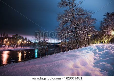 the little river and the multi-storey houses at the distant shore at snowy night