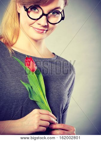 Delicacy and subtlety of women. Young adorable woman with spring flower. Portrait of beauty delicate girl in glasses with red beautiful tulip.