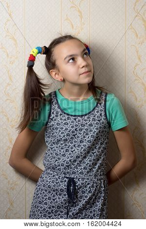11 year old girl is leaning against the wall and looks up dreamily