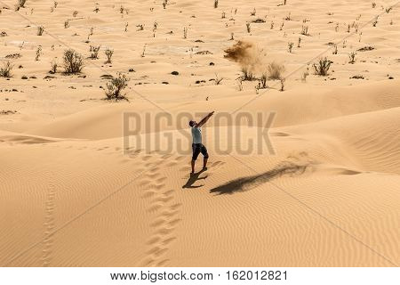 Man tourist in desert rub al khali in Oman throwing sand 3