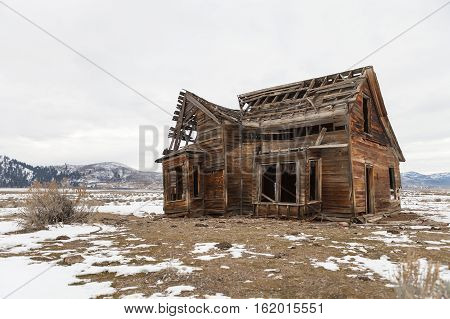 Old abandoned farm house in winter with snow.