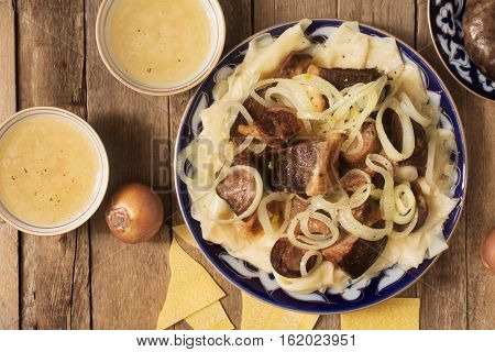 National Kazakh dish - Beshbarmak prepared with meat and pasta on the rustic wooden table