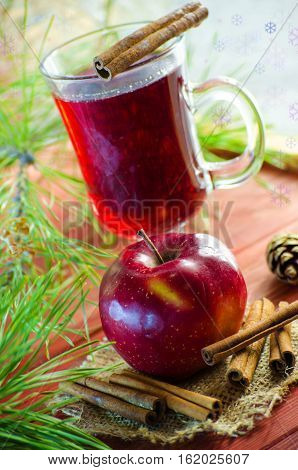 Spicy Christmas drink in a glass with spices on a background of trees