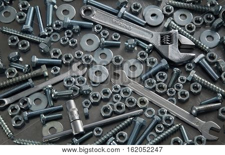 Bolts screws nuts wrenches on a metal sheet.