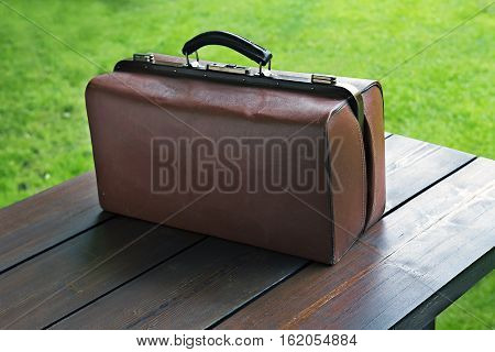 Old suitcase on a wooden table in the garden