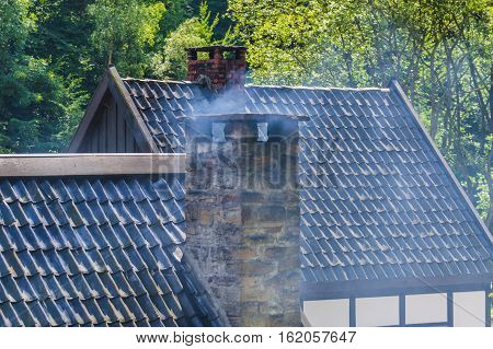 Smoking chimney on the roof of a house.