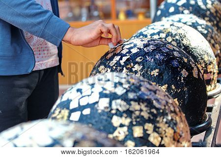 Gilding Gold Leaf To Round Stones Embedded For Worship Buddha.