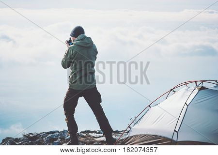 Man photographer with photo camera shooting foggy mountains clouds landscape from tent camping Travel Lifestyle concept adventure vacations outdoor