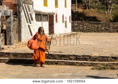 Bandipur, Nepal - NOVEMBER 24, 2016: Nepali aged pilgrim in orange robe in the temple of Bandipur in Nepal November 24 2016.
